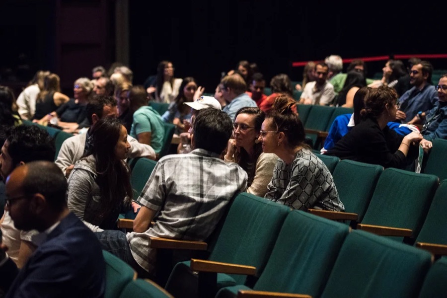 A theatre full of conference attendees who have turned around in their seats to talk to each other.